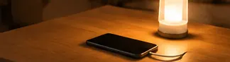 停電時、木製の机の上でスマートフォンを充電しながらランタンで手元を照らしている様子